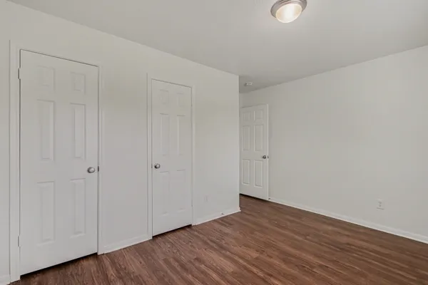 a view of an empty room with wooden floor and windows