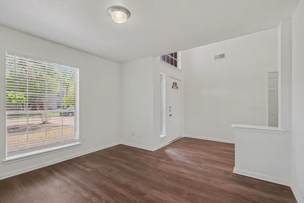 an empty room with windows a fireplace and wooden floor