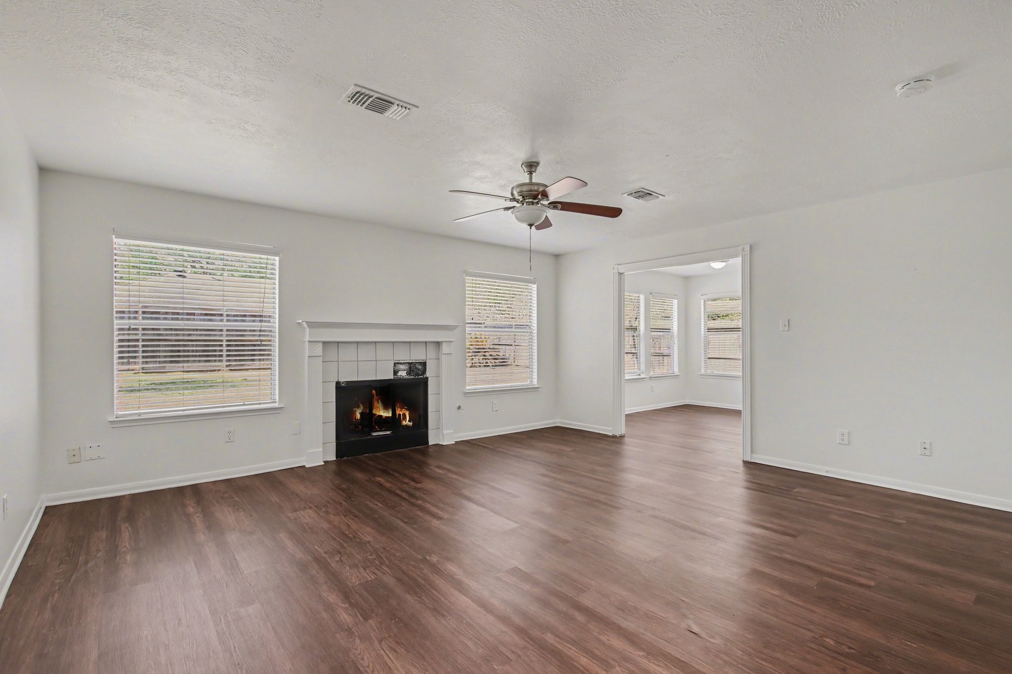 7203 Glen Rosa Drive Katy, TX 77494 - Photo 7 of 28 an empty room with windows a fireplace and wooden floor