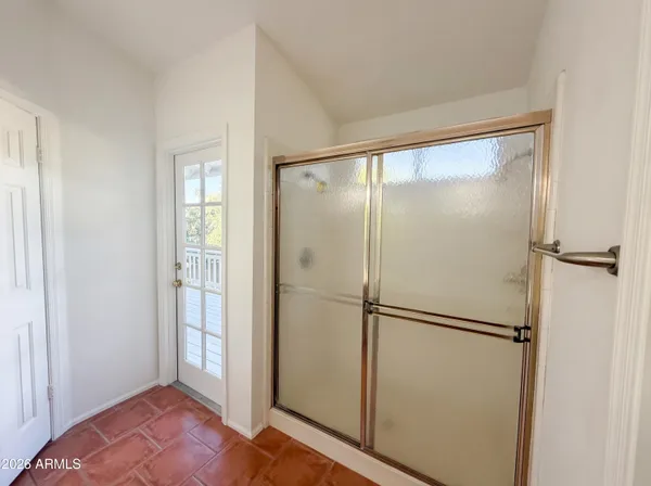 an empty room with a chandelier fan and wooden floor