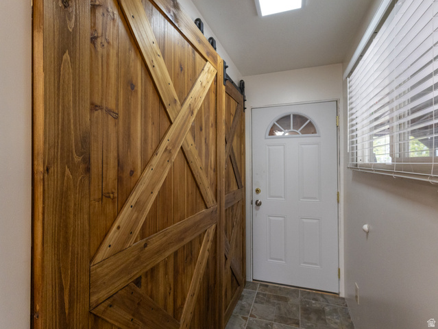 5082 Pine Crest Road Evanston, UT 82930 - Photo 13 of 25 Rustic wood barn door with black hardware, complementing the white exterior door with an arched window