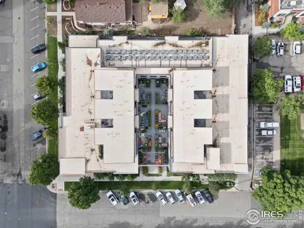 a view of a white building with plants in front of it