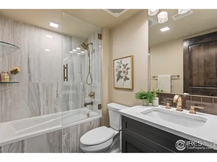 a bathroom with a granite countertop sink toilet a mirror a bathtub and shower