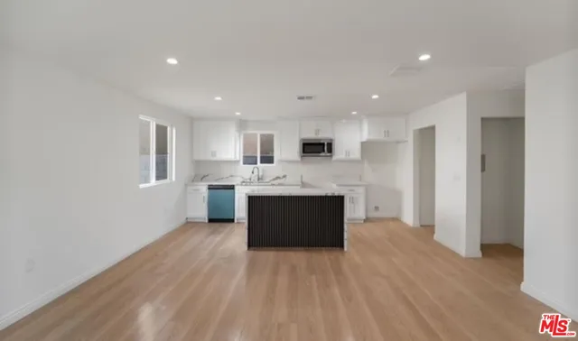 a large kitchen with a sink and dishwasher a refrigerator with wooden floor