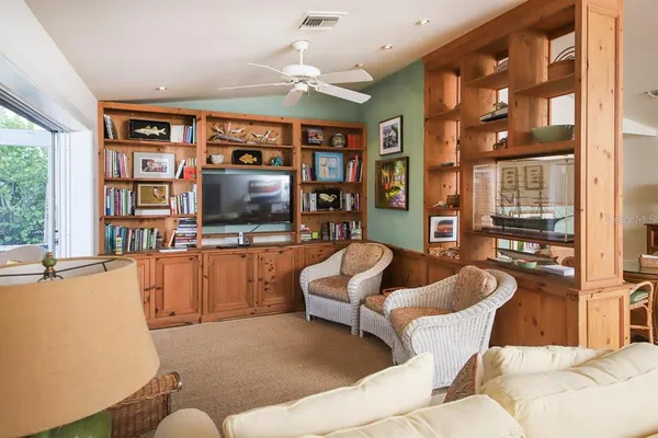 a living room with furniture a flat screen tv and a floor to ceiling window