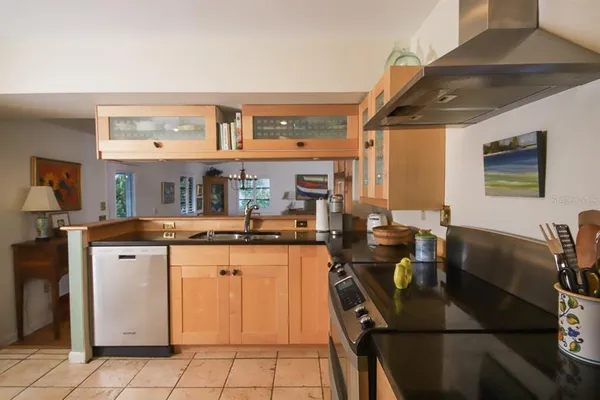 a kitchen with stainless steel appliances granite countertop a stove top oven a sink dishwasher and cabinets with wooden floor