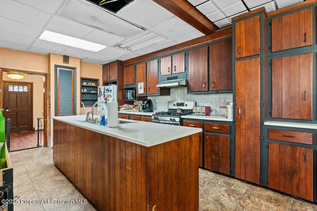 a kitchen with stainless steel appliances granite countertop a stove a sink dishwasher and a refrigerator with wooden cabinets