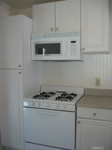 a kitchen with granite countertop white cabinets and white appliances