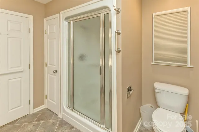 a bathroom with a toilet shower and a window
