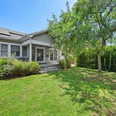a backyard of a house with plants and large tree