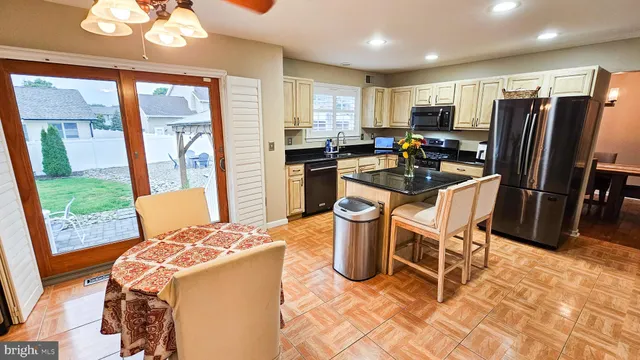 a dining room with stainless steel appliances granite countertop a table chairs and a refrigerator