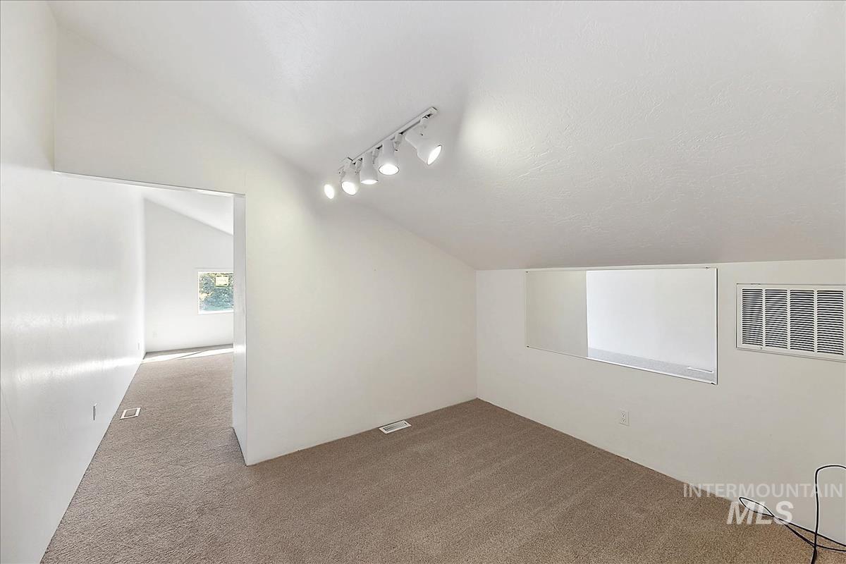 2804 West Sunrise Rim Road Boise, ID 83705 - Photo 31 of 50 Carpeted room with a vaulted ceiling, track lighting, and a horizontal window