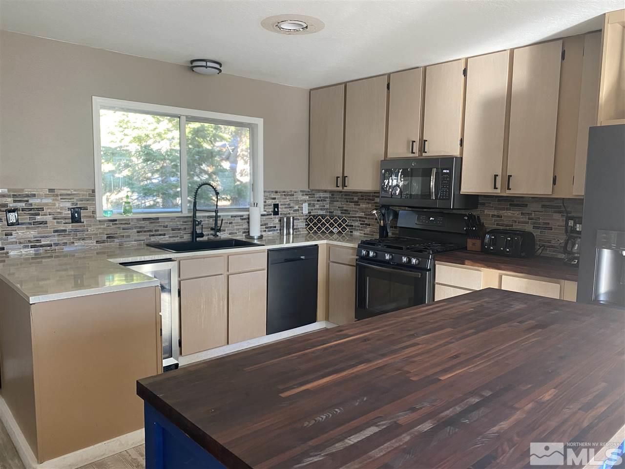 321 Barton Drive Stateline, NV 89449 - Photo 3 of 23 a kitchen with stainless steel appliances granite countertop wooden cabinets a stove top oven a sink and dishwasher with wooden floor