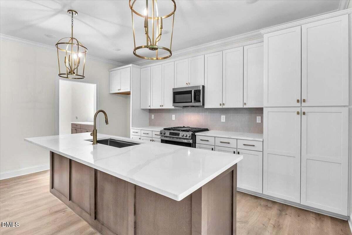 12845 Mallard Rock Road Zebulon, NC 27597 - Photo 31 of 63 a kitchen with stainless steel appliances a sink a stove a microwave cabinets and wooden floor