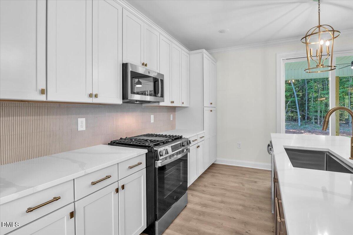12845 Mallard Rock Road Zebulon, NC 27597 - Photo 35 of 63 a kitchen with stainless steel appliances granite countertop a sink a stove and a wooden floors