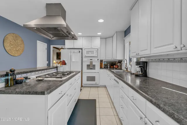 a kitchen with granite countertop stainless steel appliances a stove refrigerator sink and cabinets