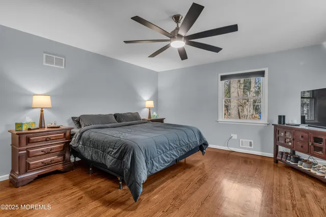 a bedroom with a bed chandelier dresser and a window