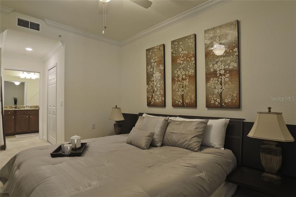 Undisclosed Address Lakewood Ranch, FL 34211 - Photo 10 of 28 a bedroom with a large bed and a lamp on table