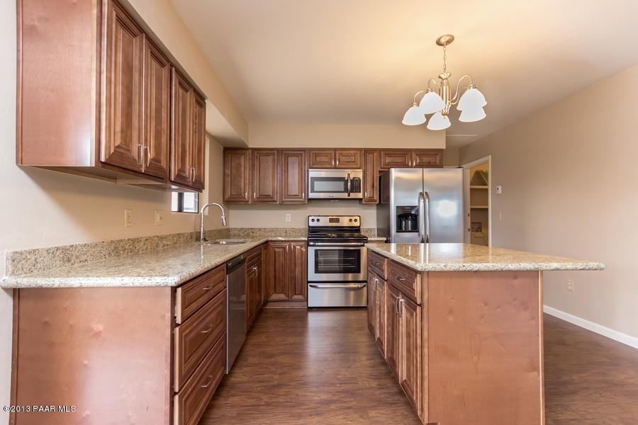 8049 East Barbara Road Prescott Valley, AZ 86314 - Photo 11 of 23 a kitchen with a center island wooden cabinets and stainless steel appliances
