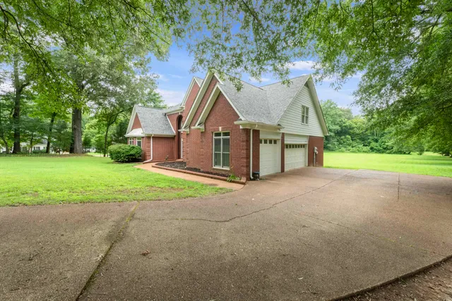 a view of a house with a yard and large trees