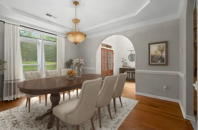 a dining room with wooden floor a chandelier a wooden table and chairs