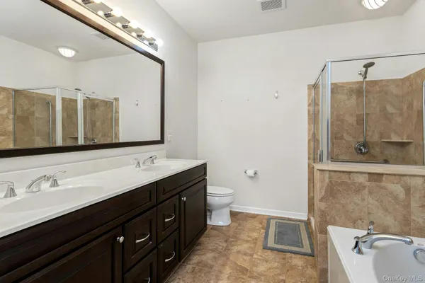 a bathroom with a double vanity sink and mirror with toilet