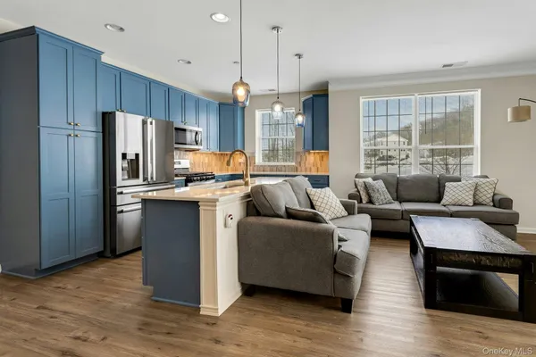 a living room with stainless steel appliances granite countertop wooden floor a couch and a window