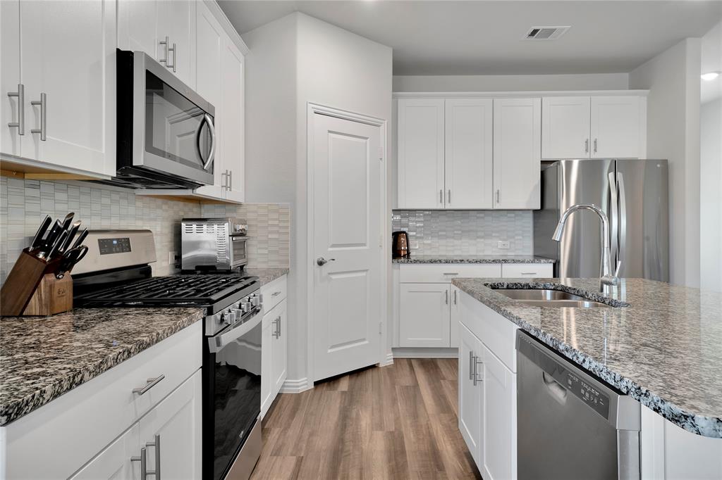 1817 Berry Rdg Trail Aubrey, TX 76227 - Photo 11 of 30 a kitchen with stainless steel appliances granite countertop a stove sink and cabinets
