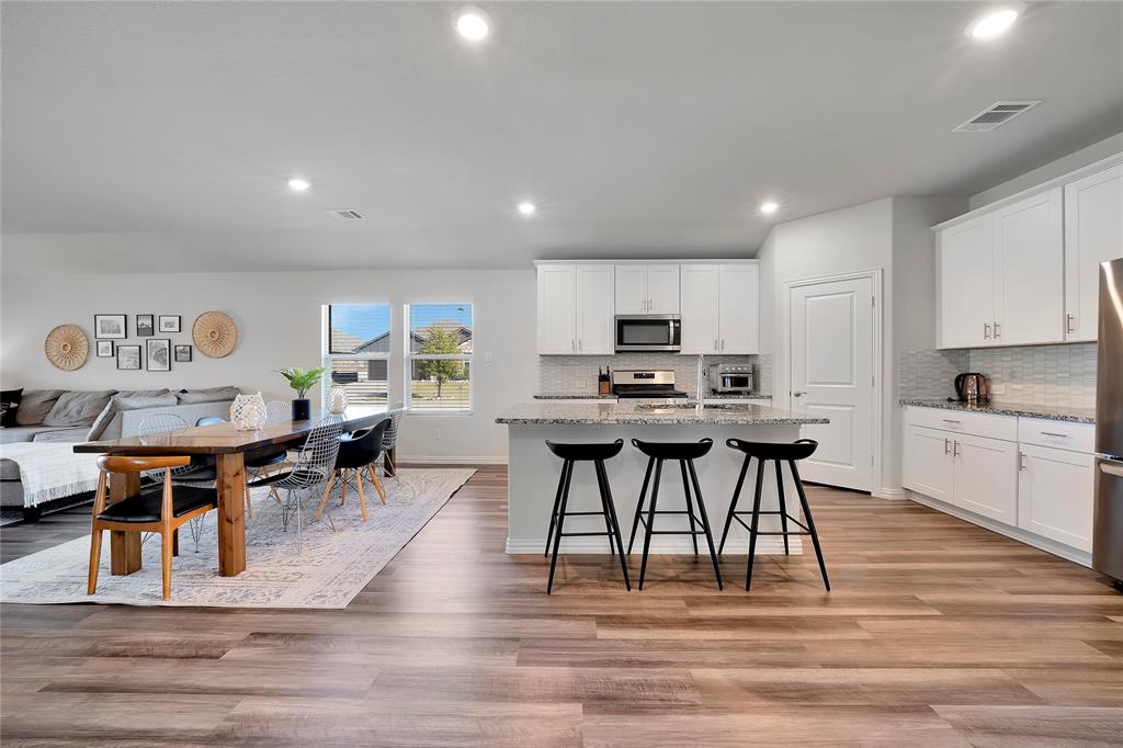 1817 Berry Rdg Trail Aubrey, TX 76227 - Photo 8 of 30 a kitchen with stainless steel appliances kitchen island granite countertop a table chairs sink and cabinets
