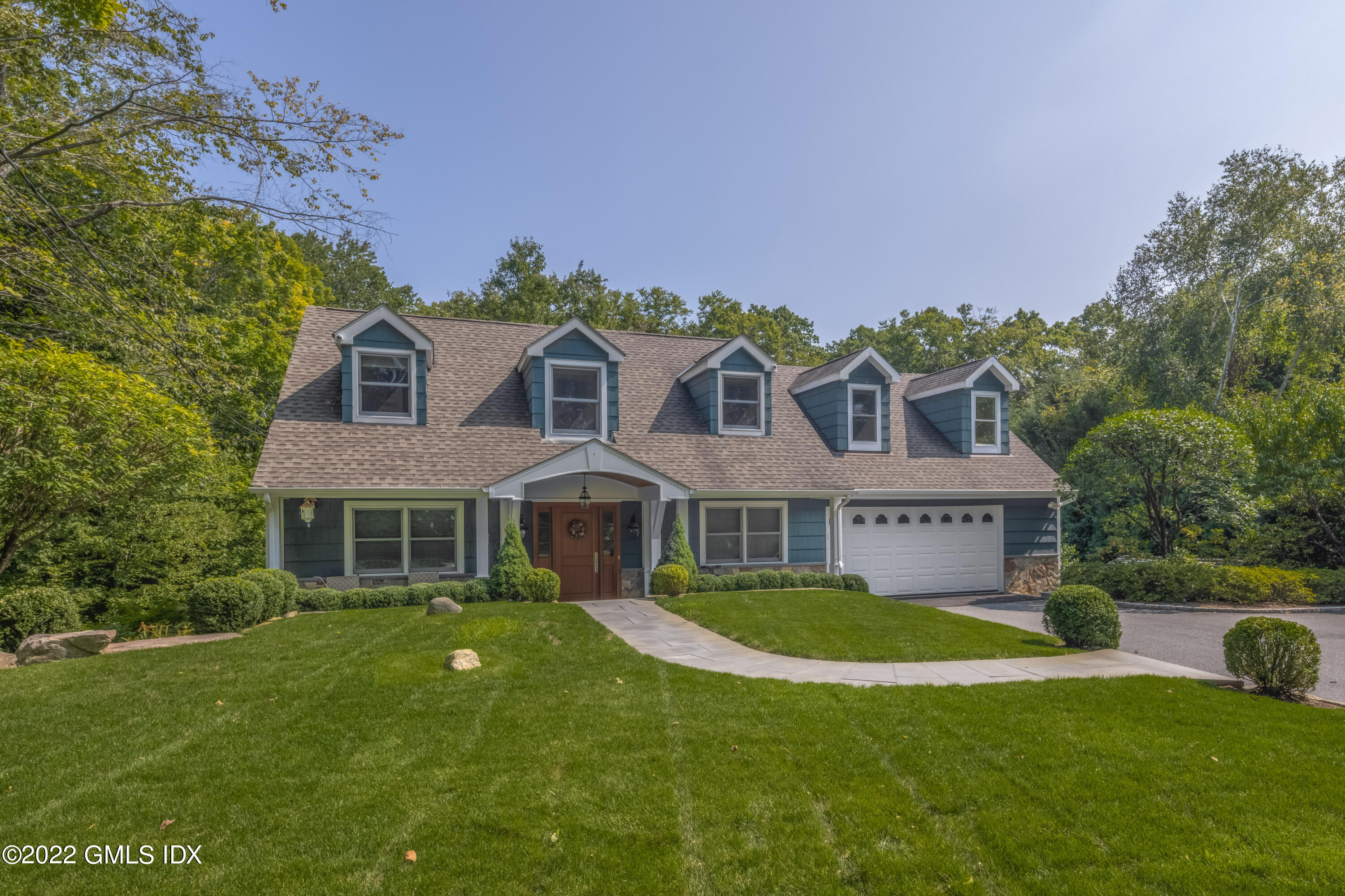 27 Rustic View Road Greenwich, CT 06830 - Photo 2 of 37 a front view of a house with a yard table and chairs