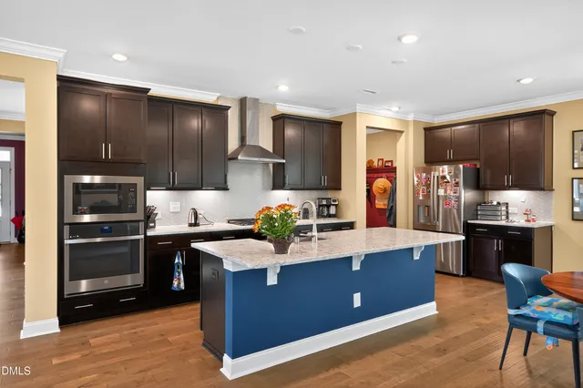 a large kitchen with stainless steel appliances kitchen island granite countertop a stove refrigerator and cabinets