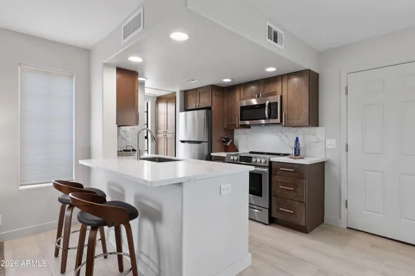 a kitchen with stainless steel appliances kitchen island granite countertop a stove top oven a sink and a refrigerator