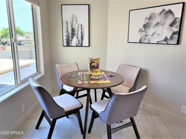 a kitchen with stainless steel appliances granite countertop a sink dishwasher a stove top oven a dining table and chairs with wooden floor