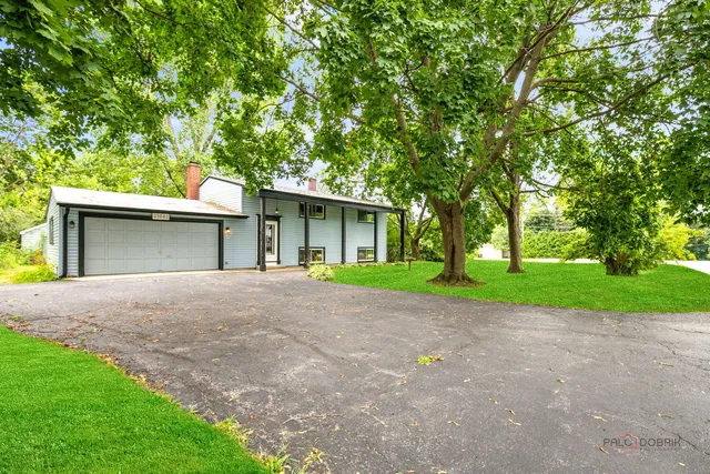 a view of a house with a yard and large tree