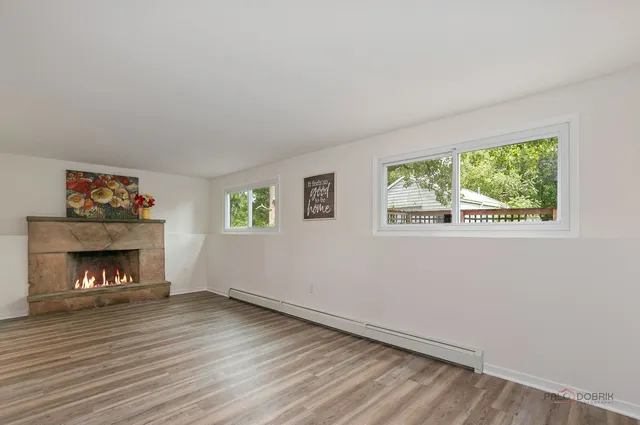 a view of an empty room with wooden floor fireplace and a window