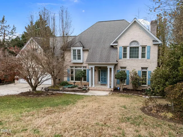 a view of a white house with large trees next to a yard