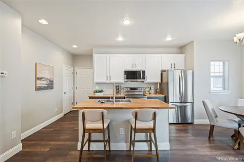 a kitchen with stainless steel appliances a dining table chairs and wooden floor