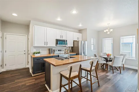 a kitchen with stainless steel appliances a stove a sink a refrigerator white cabinets and wooden floor