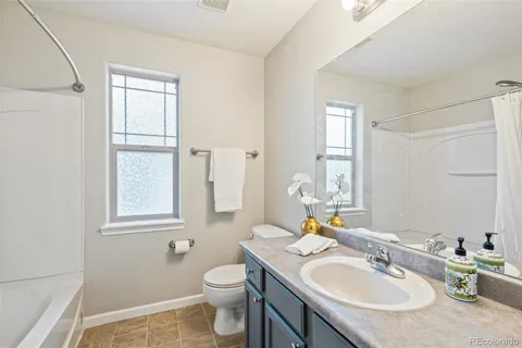 a bathroom with a granite countertop sink toilet and mirror