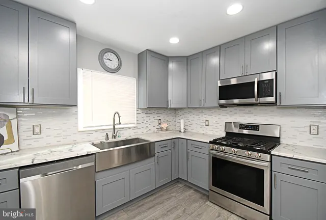 a kitchen with stainless steel appliances granite countertop a sink a stove a microwave and wooden cabinets