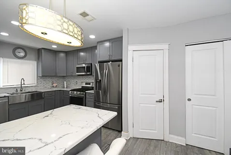 a kitchen with a refrigerator a sink dishwasher and wooden cabinets with wooden floor