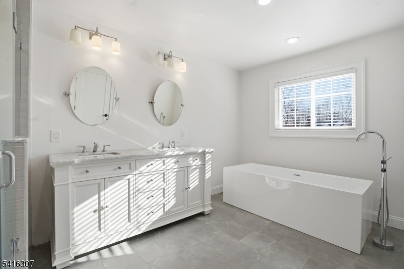 44 Manor Road Livingston, NJ 07039 - Photo 23 of 48 a spacious bathroom with a double vanity sink large mirror and a bathtub