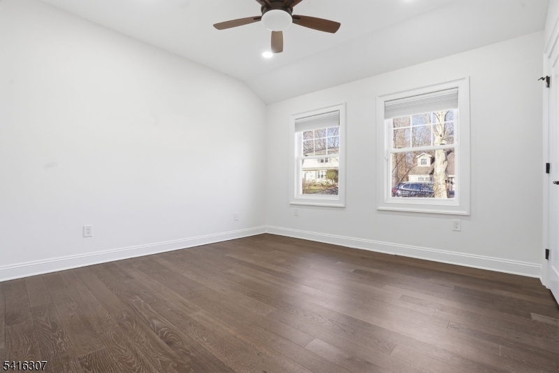 44 Manor Road Livingston, NJ 07039 - Photo 30 of 48 an empty room with wooden floor chandelier fan and windows