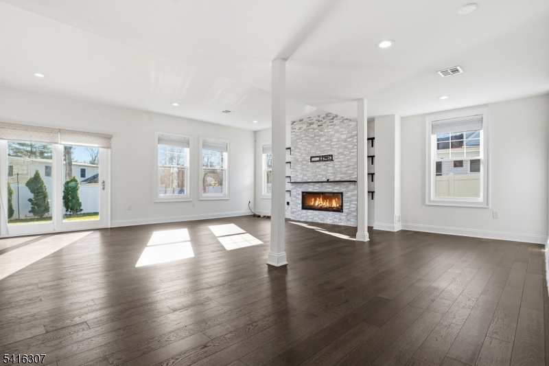 44 Manor Road Livingston, NJ 07039 - Photo 8 of 48 an empty room with windows a fireplace and wooden floor