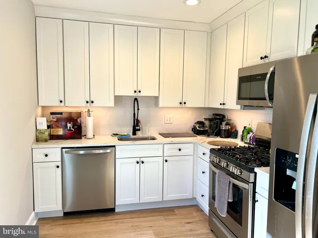 a kitchen with stainless steel appliances granite countertop a stove a sink and white cabinets