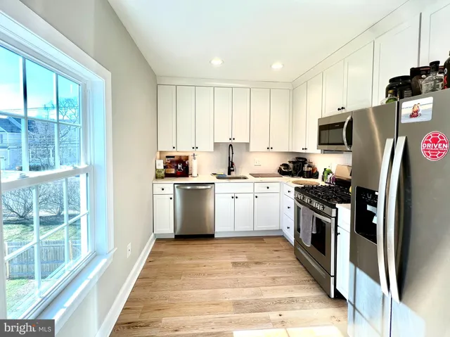 a kitchen with granite countertop a refrigerator oven a sink dishwasher and a stove with wooden floor