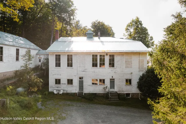 a view of a white house with a yard and table and chairs under an umbrella