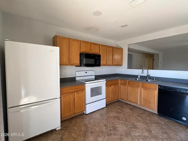 a white kitchen with stainless steel appliances granite countertop a refrigerator a stove a sink and a microwave