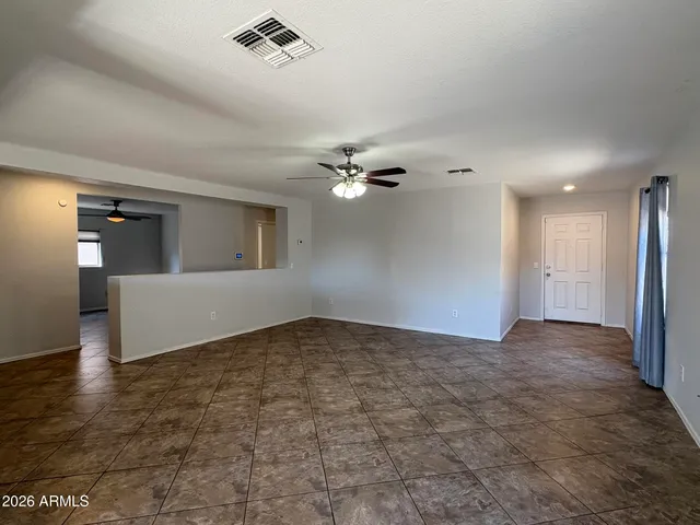 a view of a big room with a chandelier fan and wooden floor