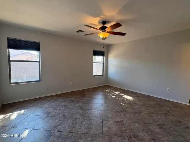 a view of an empty room with window and chandelier fan